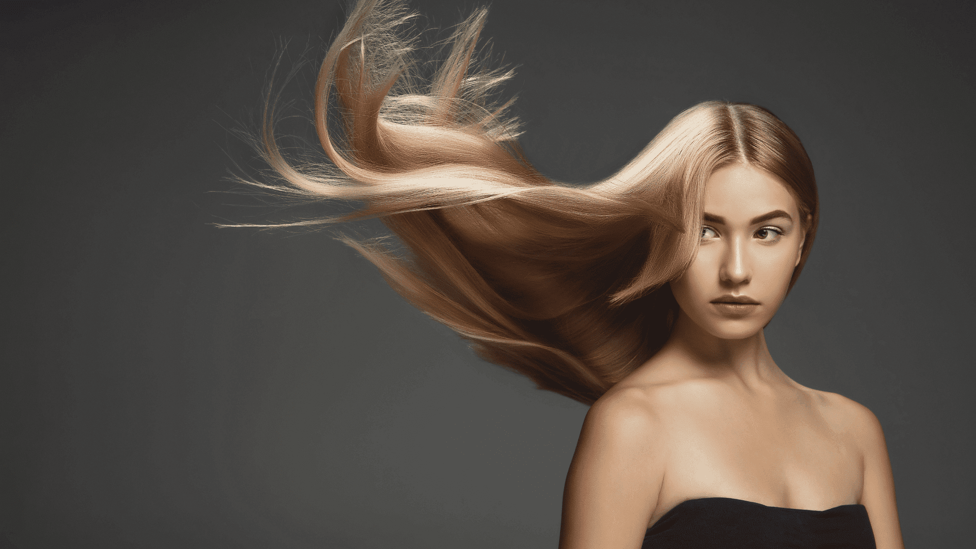 Young woman with long flowing hair against a dark background.
